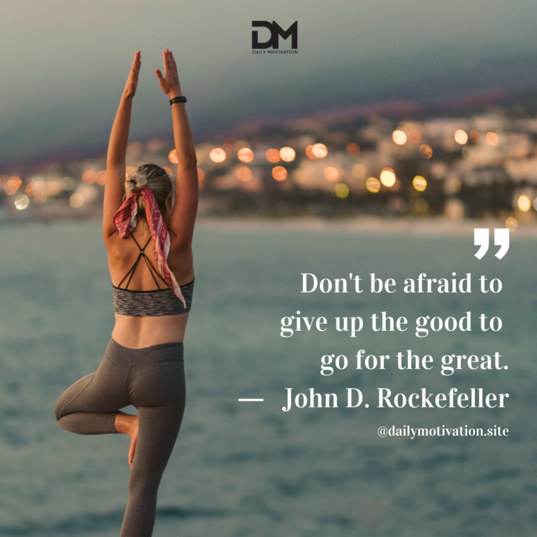 A woman stands in tree pose in front of a body of water.