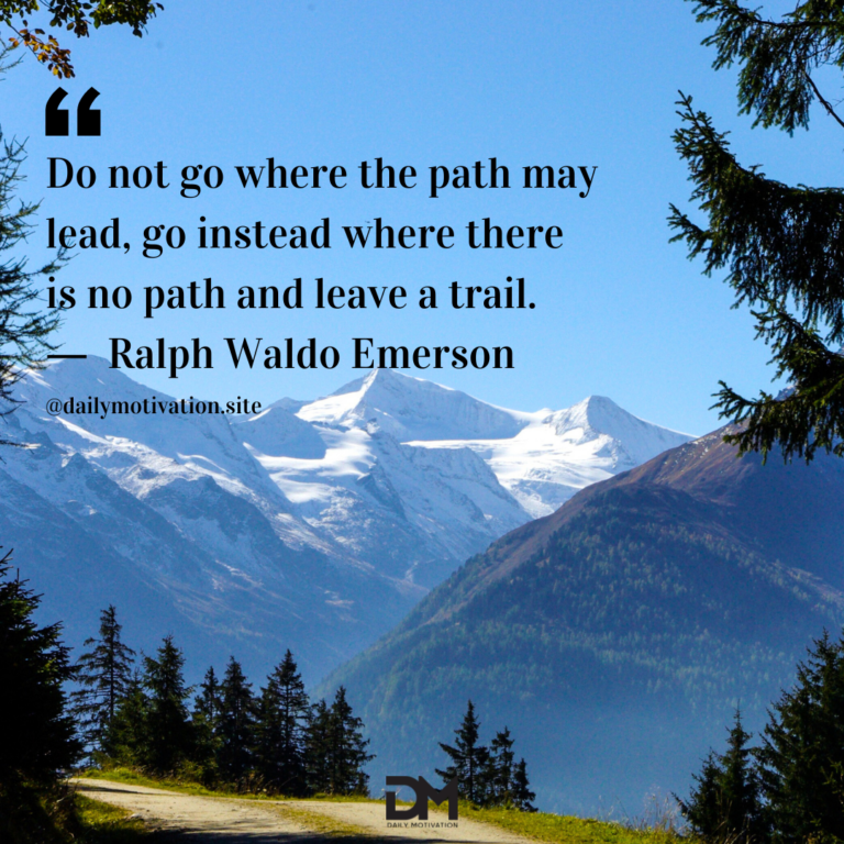 A view of a small yellow field amidst a backdrop of a huge snowy mountain range.