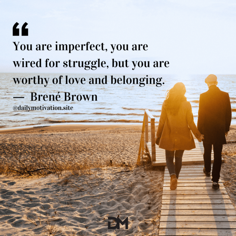 A couple hold hands and stroll along a boardwalk leading to the beach and sea beyond.