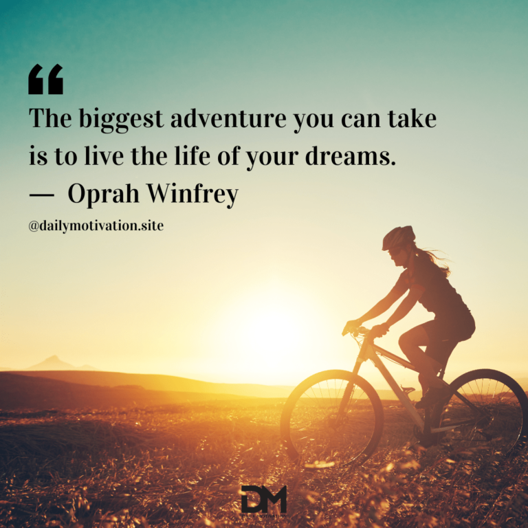 A woman rides a bike along a rocky terrain with the sun rising behind her.