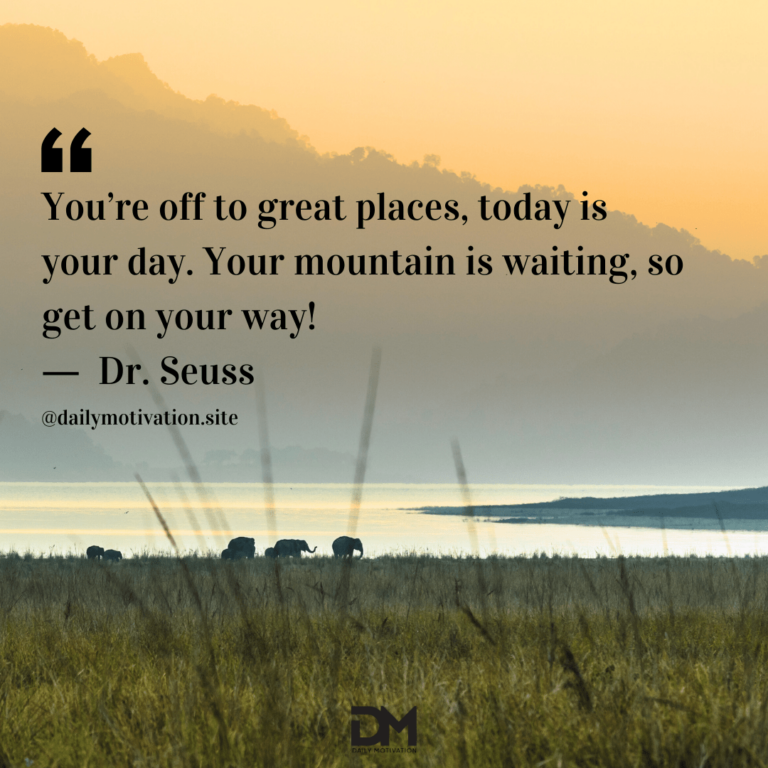 Elephants walk along a lake in the distance with a hazy big hill in the background.