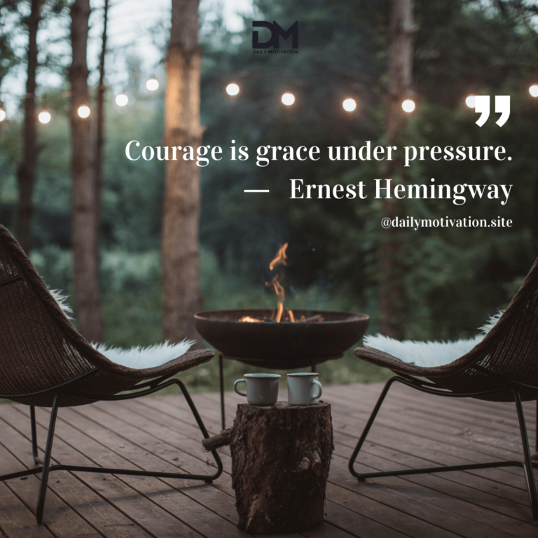Two chairs sit beside a small fire on a wooden deck facing the forest.