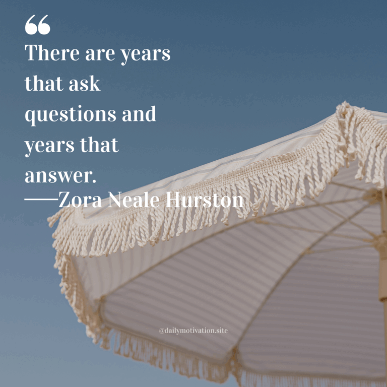 Cream-colored beach umbrella with fringed edges set against a clear blue sky.