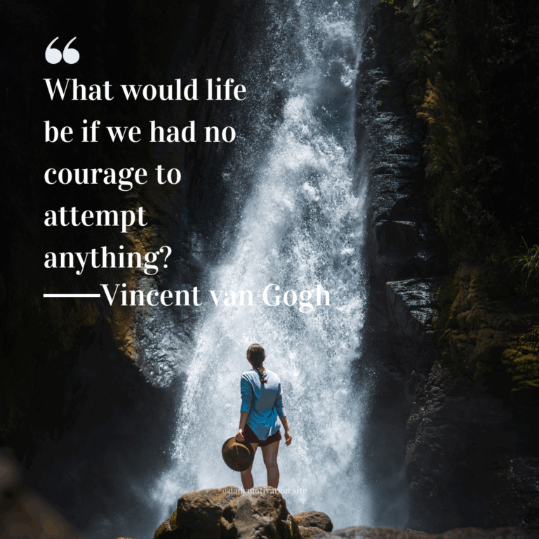 Woman standing before a tall waterfall holding a hat, surrounded by mist and rocks.